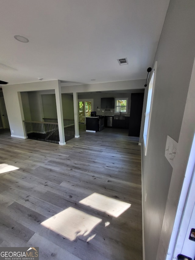 unfurnished living room with baseboards, visible vents, and wood finished floors