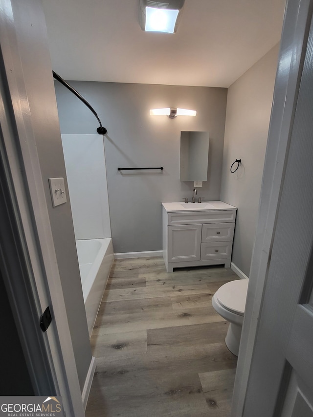 bathroom with toilet, baseboards, wood finished floors, and vanity