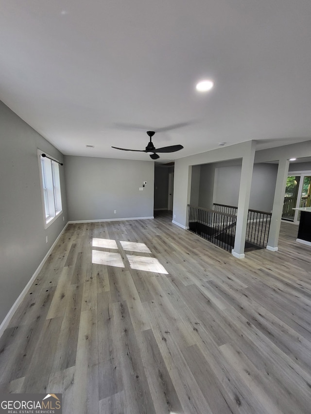 unfurnished living room featuring baseboards, light wood-style flooring, and ceiling fan