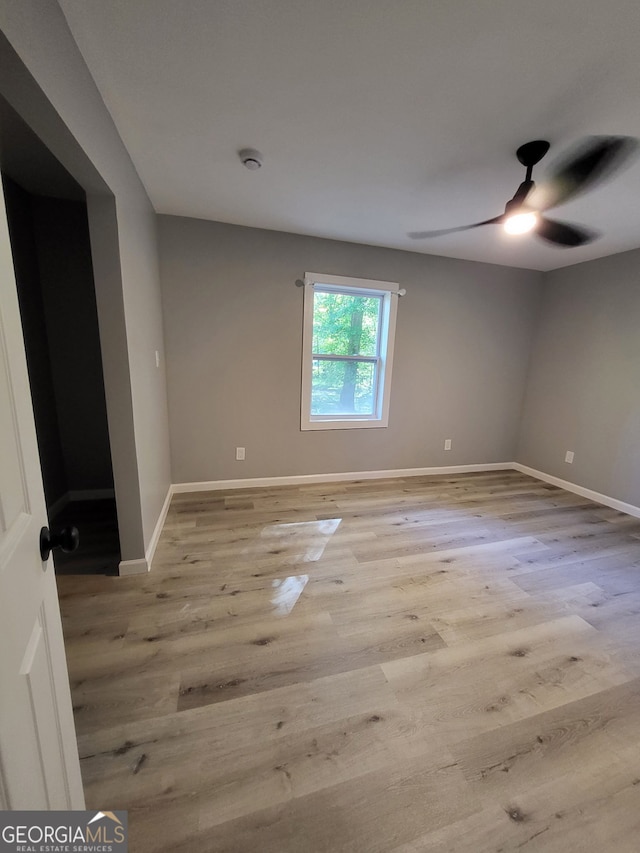unfurnished room with wood finished floors, baseboards, and ceiling fan