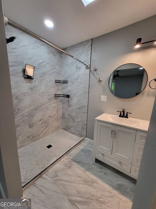 bathroom featuring vanity, marble finish floor, a tile shower, and recessed lighting