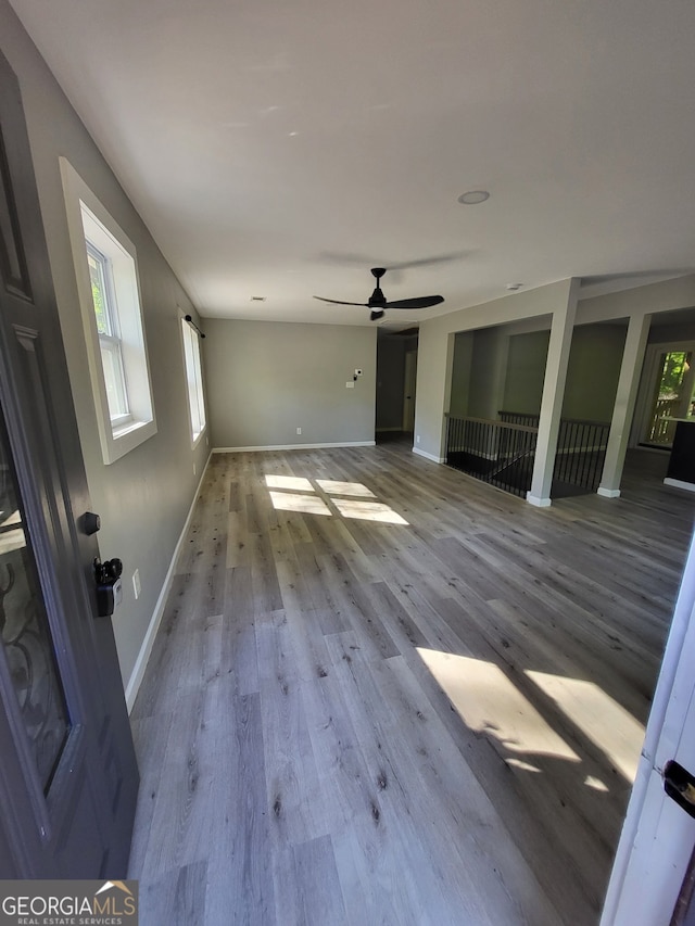 unfurnished living room with ceiling fan, baseboards, and wood finished floors