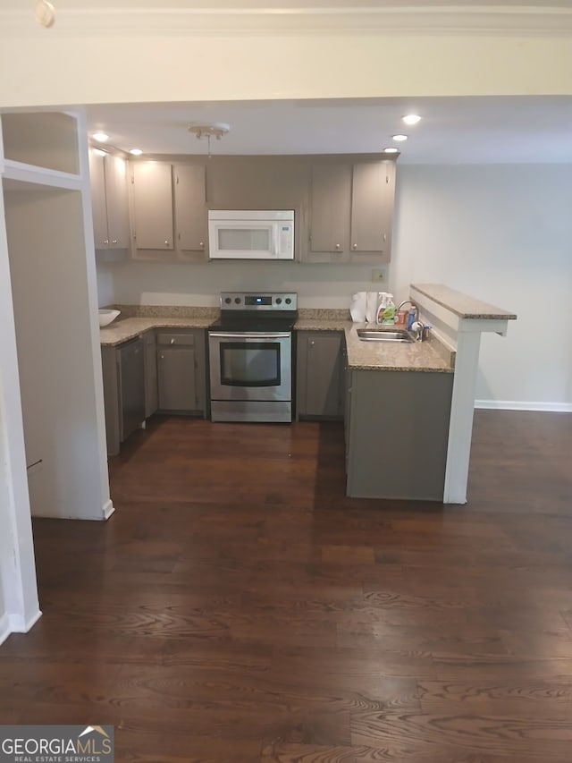 kitchen featuring a peninsula, stainless steel appliances, gray cabinetry, and dark wood-style floors