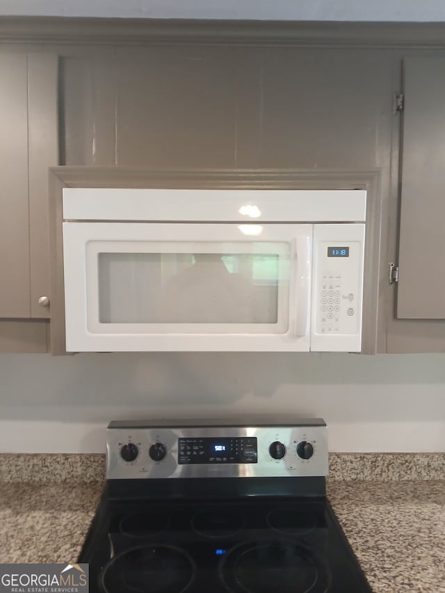 interior details with white microwave, electric stove, and gray cabinets