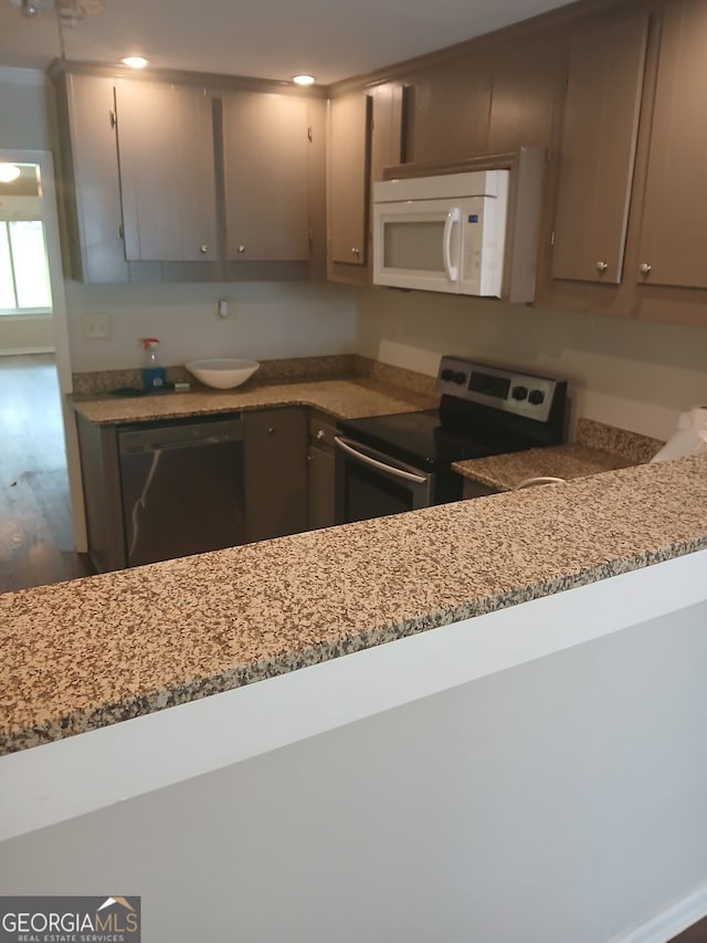 kitchen with light stone countertops, wood finished floors, gray cabinets, and appliances with stainless steel finishes