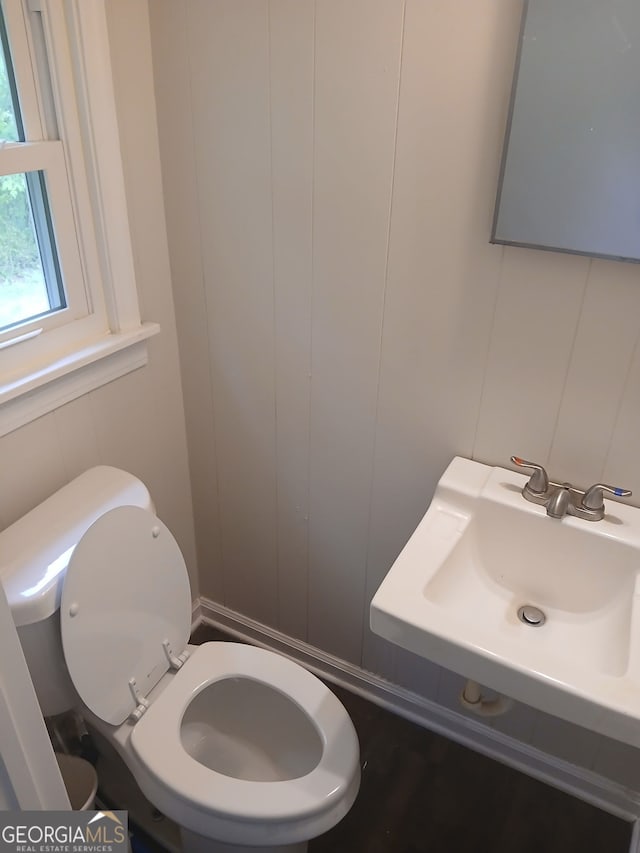 bathroom with toilet, a decorative wall, and a sink