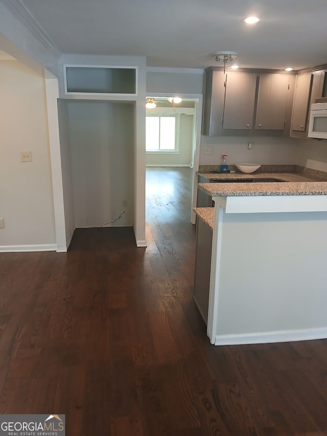 kitchen featuring light stone countertops, recessed lighting, dark wood-style flooring, white microwave, and gray cabinets