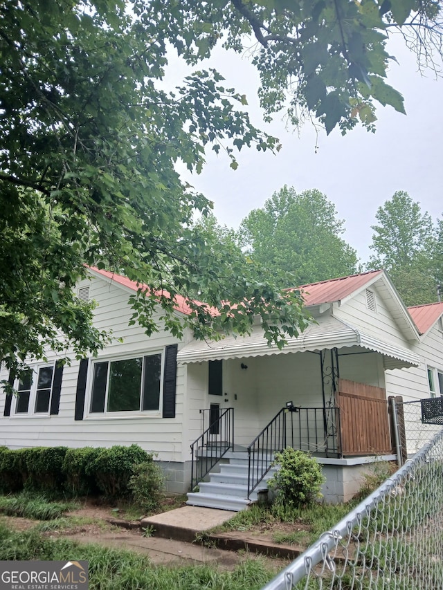 view of front of house featuring fence and metal roof