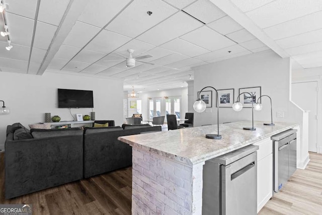 kitchen featuring fridge, light stone counters, light wood-style flooring, and open floor plan
