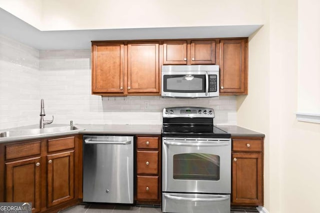 kitchen with decorative backsplash, stainless steel appliances, brown cabinets, and a sink