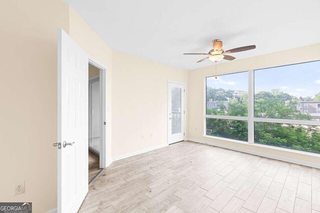 unfurnished bedroom featuring baseboards, access to outside, light wood-style flooring, and ceiling fan