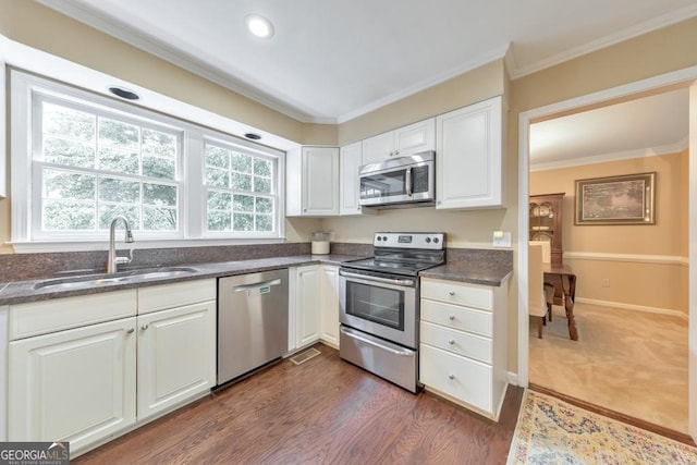 kitchen with stainless steel appliances, a sink, white cabinets, ornamental molding, and recessed lighting