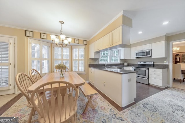 kitchen with appliances with stainless steel finishes, a chandelier, dark countertops, a sink, and ornamental molding