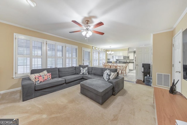 living room featuring a ceiling fan, ornamental molding, a chandelier, baseboards, and light colored carpet