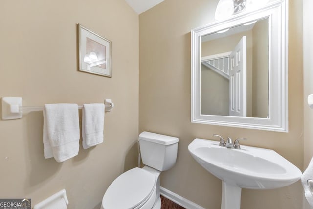 bathroom with toilet, a sink, and baseboards