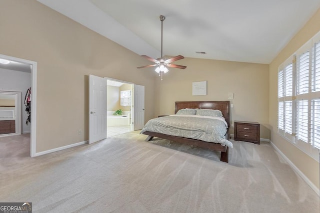 carpeted bedroom featuring lofted ceiling, a walk in closet, baseboards, ensuite bath, and a ceiling fan