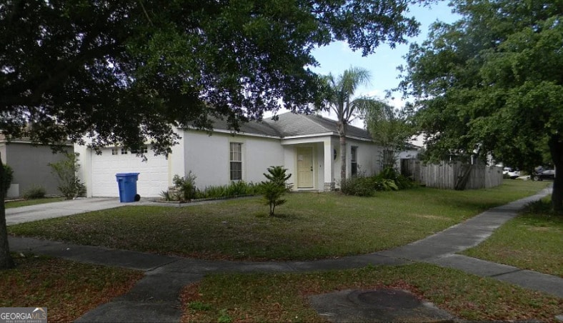 view of front of property with a garage, stucco siding, a front lawn, and driveway