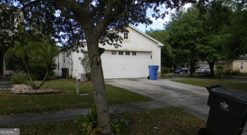 view of side of property with concrete driveway, stucco siding, and a garage