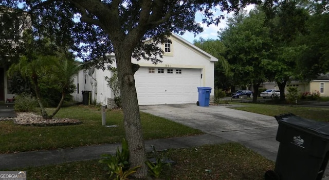 view of side of property with concrete driveway, stucco siding, and a garage