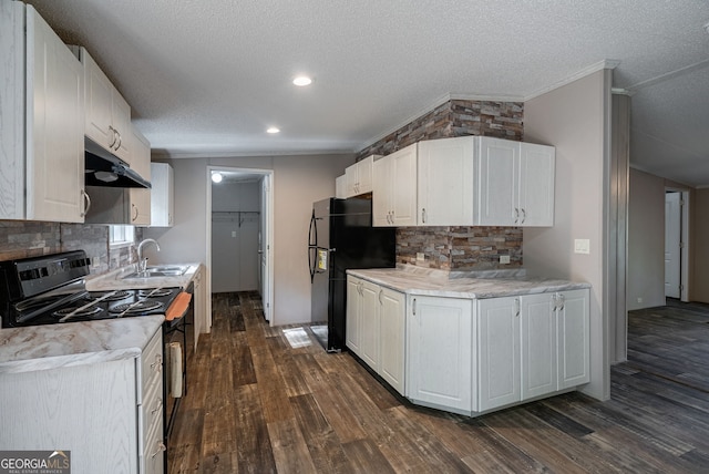 kitchen featuring a sink, black appliances, under cabinet range hood, crown molding, and dark wood-style floors