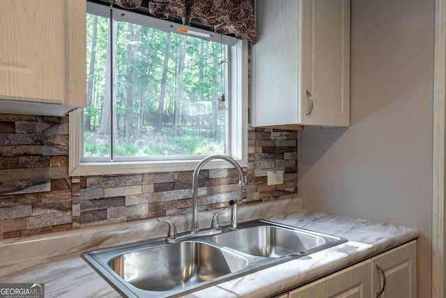 kitchen with a healthy amount of sunlight, light countertops, tasteful backsplash, and a sink