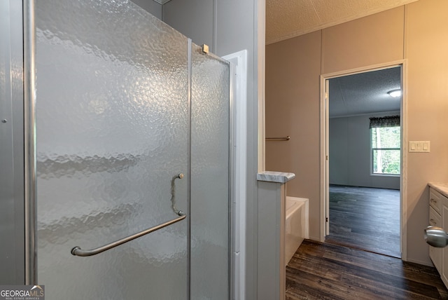 bathroom featuring a textured ceiling, wood finished floors, a shower stall, and a tub to relax in