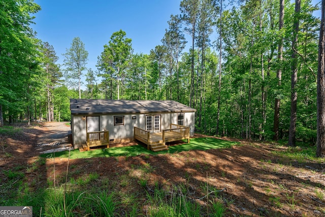 rear view of property featuring a wooden deck and crawl space