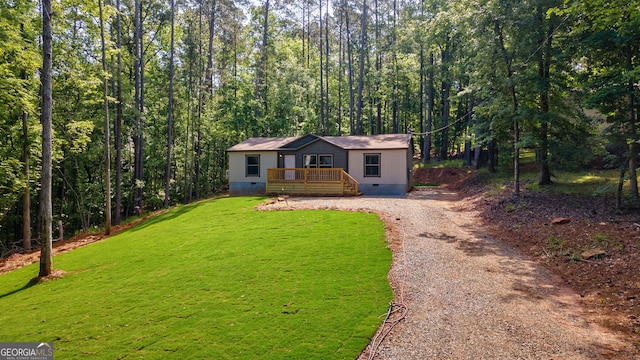 manufactured / mobile home featuring a deck, crawl space, a front lawn, gravel driveway, and a forest view
