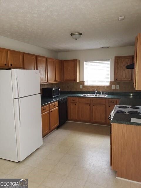 2075 Tussahaw Xing, Mcdonough, GA 30252 - kitchen featuring freestanding refrigerator, black dishwasher, a sink, brown cabinetry, and dark countertops