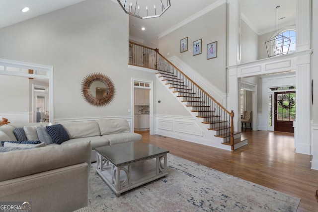 living area with stairs, a high ceiling, a chandelier, plenty of natural light, and wood finished floors