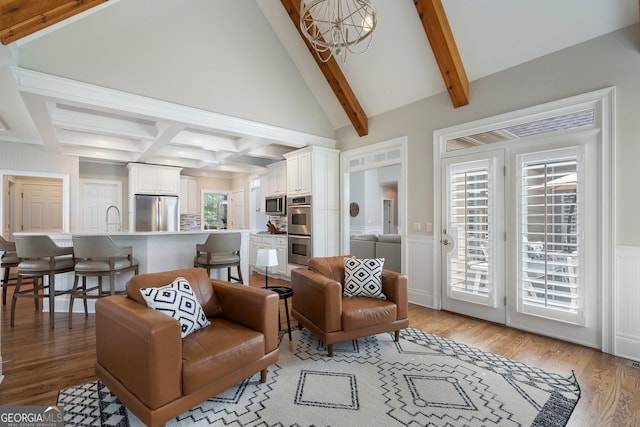 living room with light wood-style flooring, a chandelier, a decorative wall, and a wainscoted wall