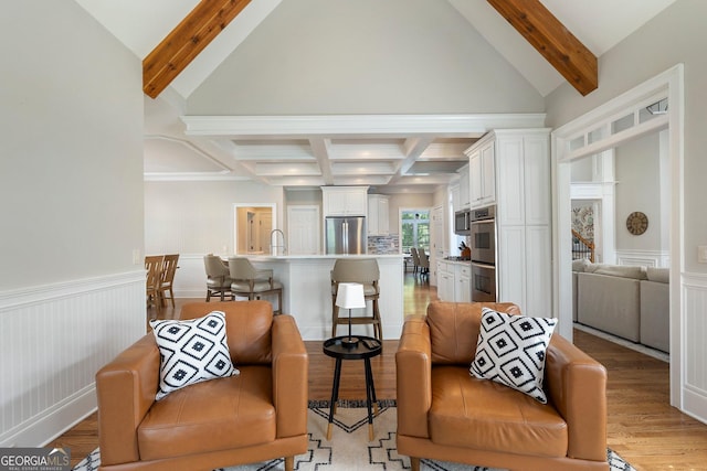 living room with light wood finished floors, wainscoting, and ornate columns