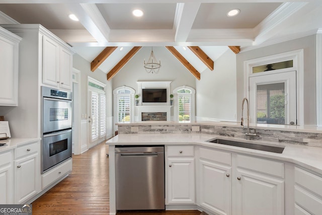 kitchen with stainless steel appliances, a sink, light countertops, white cabinets, and ornamental molding
