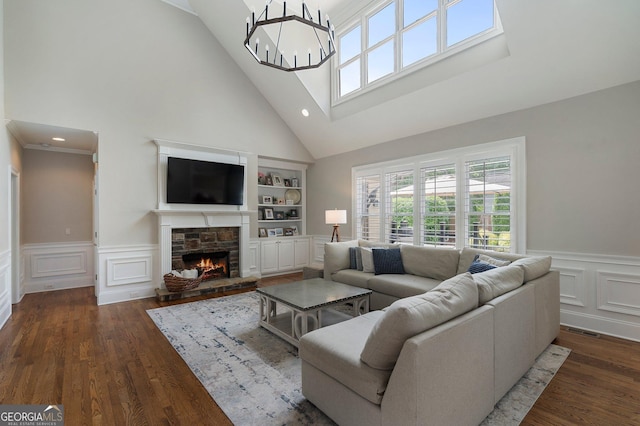 living room featuring high vaulted ceiling, a decorative wall, a chandelier, dark wood-style flooring, and a fireplace