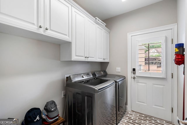 clothes washing area featuring washing machine and clothes dryer, cabinet space, and brick patterned flooring