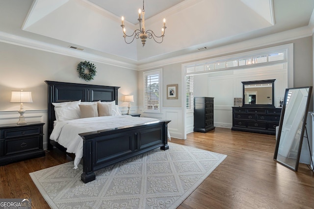 bedroom featuring a chandelier, ornamental molding, dark wood-style floors, a decorative wall, and wainscoting