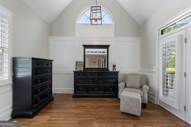 sitting room with lofted ceiling, a decorative wall, wood finished floors, and wainscoting