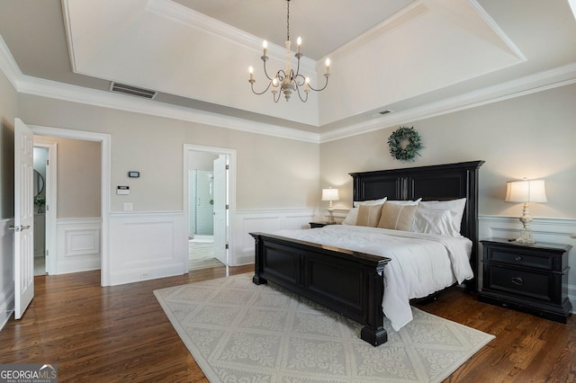 bedroom featuring a chandelier, dark wood-type flooring, wainscoting, a decorative wall, and ornamental molding