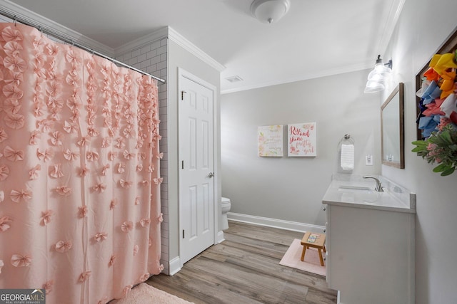 bathroom with ornamental molding, toilet, wood finished floors, vanity, and baseboards