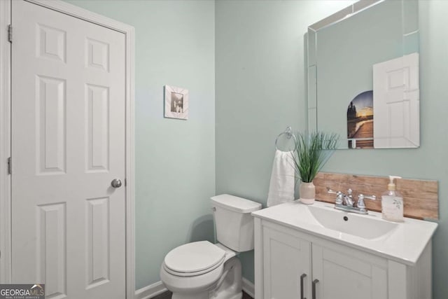 bathroom with toilet, baseboards, and vanity