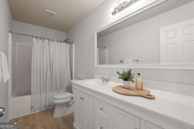 full bath with shower / bath combo with shower curtain, toilet, visible vents, vanity, and wood finished floors