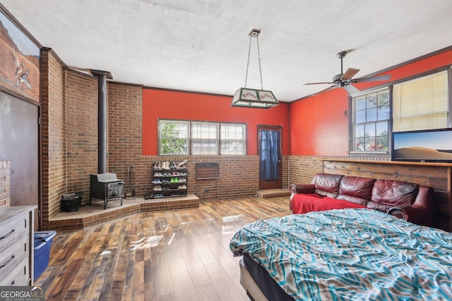 1240 C M Copelan Rd, Madison, GA 30650 - bedroom featuring a wood stove, brick wall, and hardwood / wood-style flooring