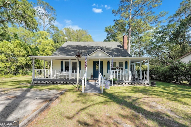 country-style home featuring a porch, a chimney, and a front yard