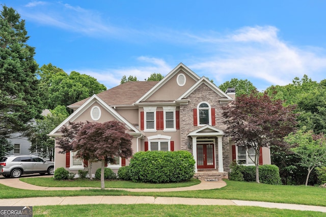 view of front facade featuring a chimney, french doors, stone siding, stucco siding, and a front yard