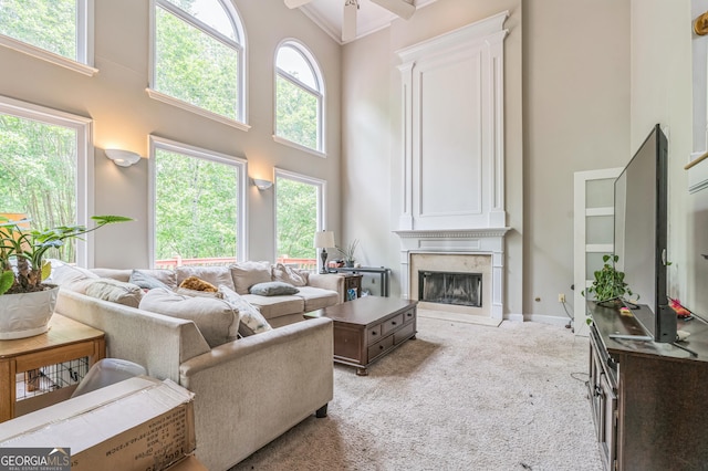 living room with a premium fireplace, light carpet, a high ceiling, and plenty of natural light