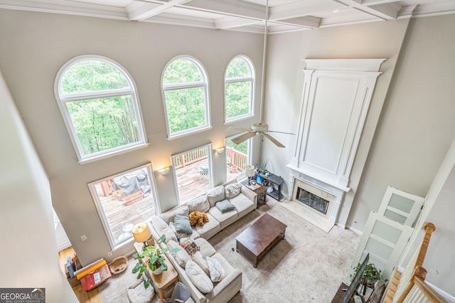 living area featuring beamed ceiling, a towering ceiling, ceiling fan, and a high end fireplace