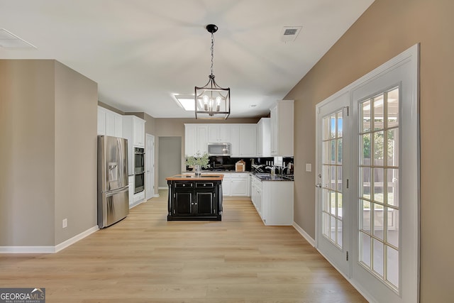 kitchen with appliances with stainless steel finishes, a sink, a chandelier, and white cabinetry