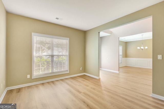 unfurnished room featuring a chandelier, light wood-style flooring, and baseboards