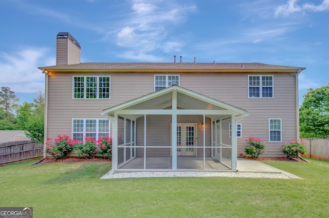 rear view of property featuring a sunroom, a chimney, and a patio area