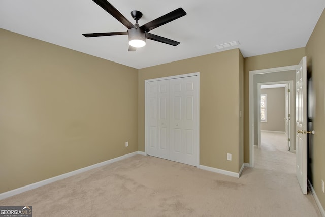 unfurnished bedroom with light carpet, a closet, baseboards, and ceiling fan